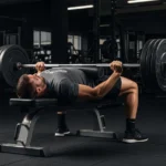athlete performing loaded barbell hip thrust glute exercise gym bench