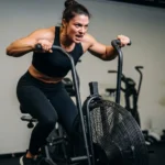 Assault Bike Training Guide: The Science of Total-Body Cardiovascular Conditioning and How to Programme It person performing assault bike training maximum effort total body cardiovascular conditioning fan bike gym