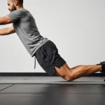 person performing Nordic hamstring curl correct form controlled eccentric descent knees on pad feet anchored gym training photography